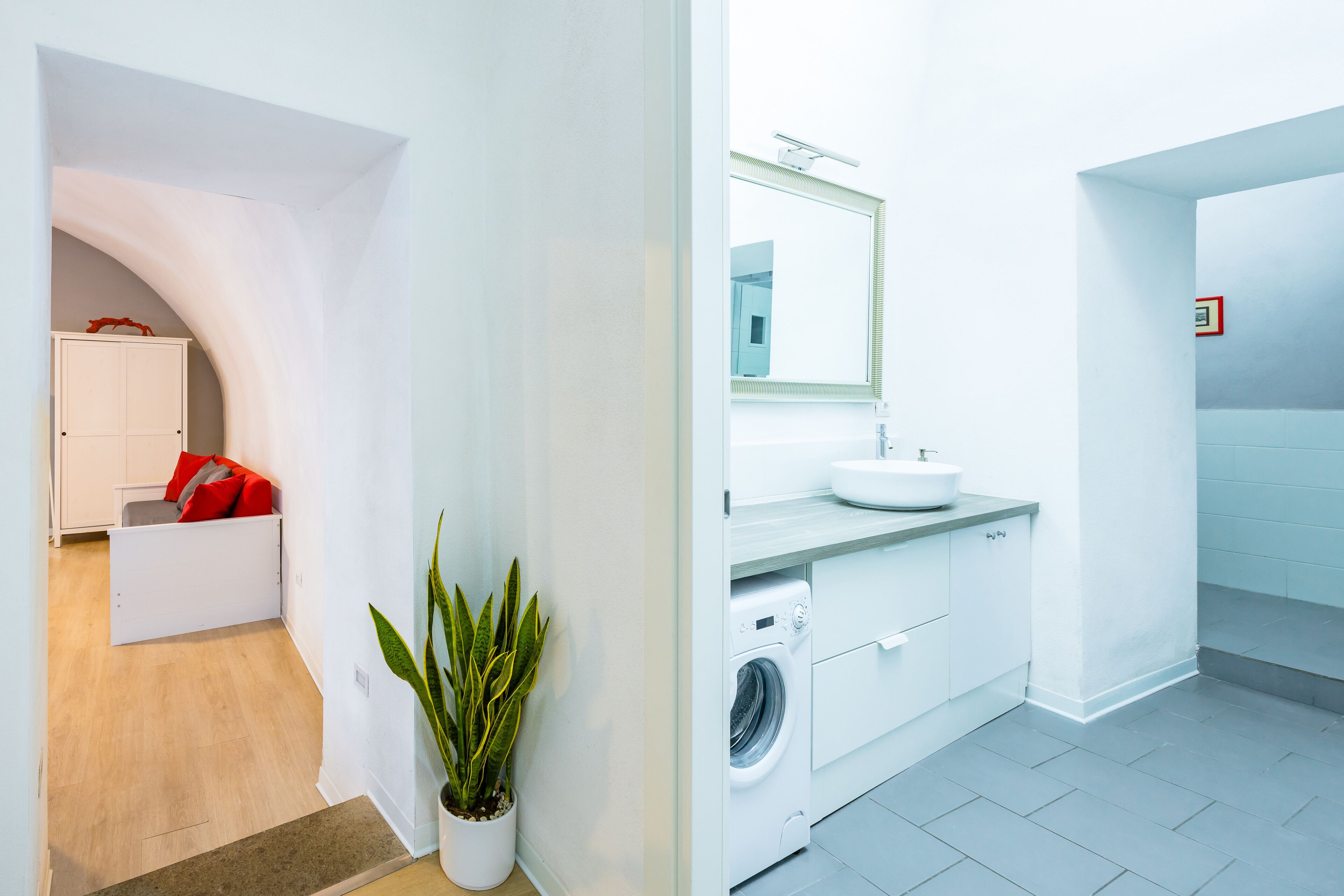 A modern bathroom with a sink, mirror, and washing machine.