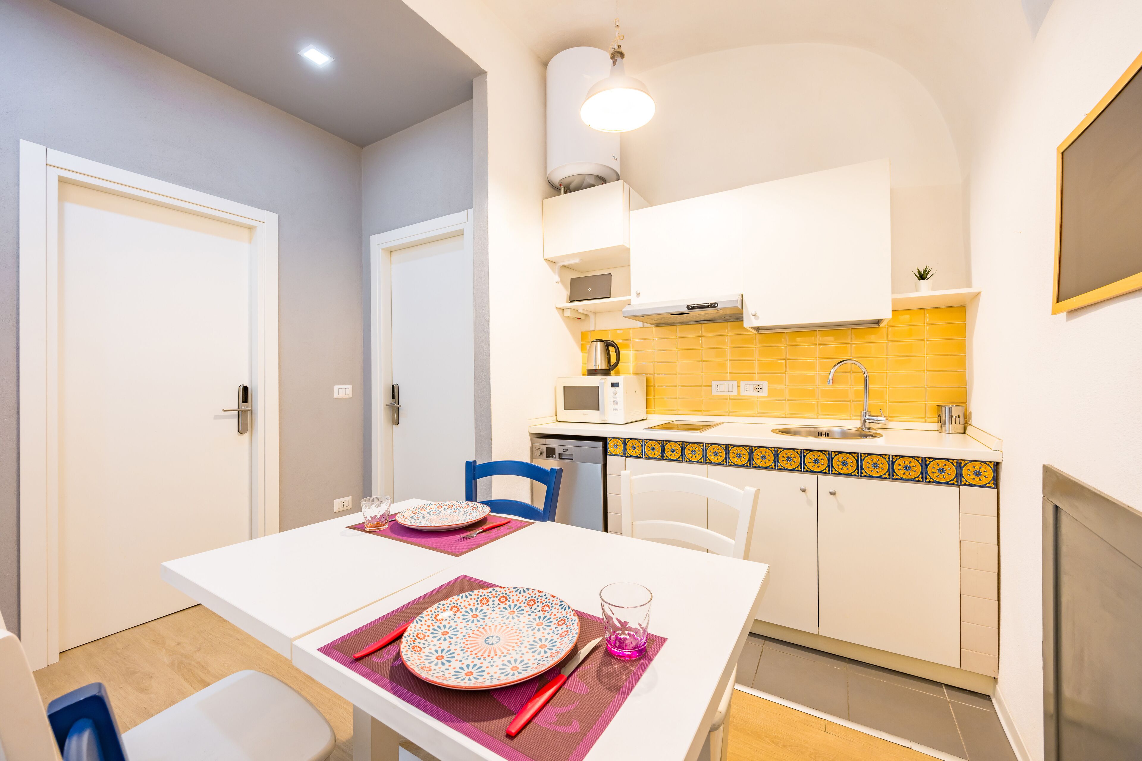 A compact kitchen with white cabinets, a yellow-tiled backsplash, and a white countertop.