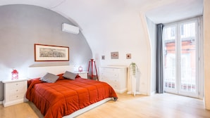 A bedroom with a bed, nightstands, a dresser, a window with curtains, and a wall-mounted air conditioner. - O Panaro Lucky Flat by NapoliApartments (Naples)