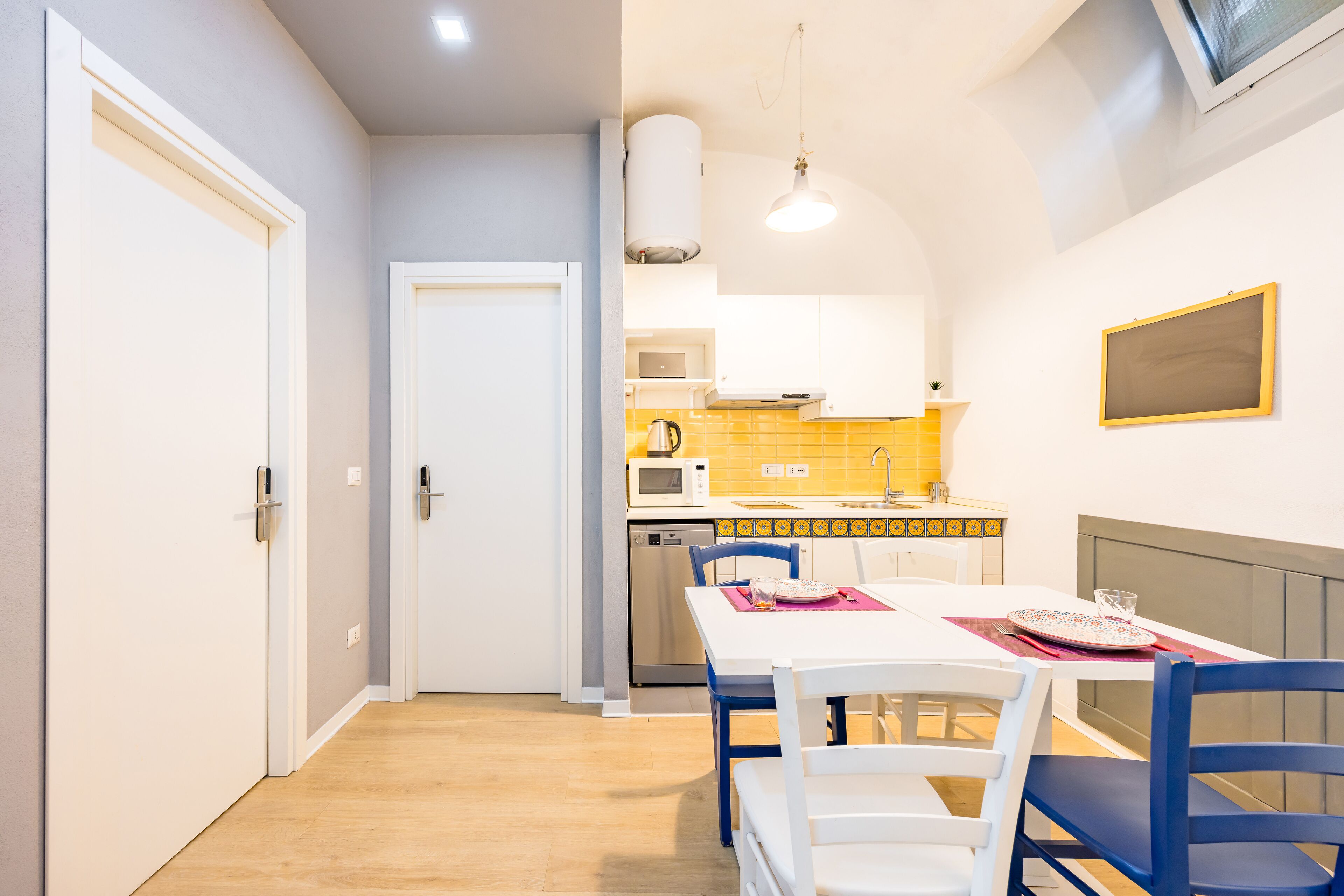 A compact kitchen with a microwave, kettle, and sink.