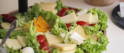 A wooden board with a salad consisting of lettuce, cheese, and cherry tomatoes.