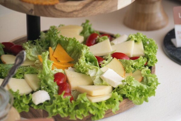 A wooden board with a salad consisting of lettuce, cheese, and cherry tomatoes.