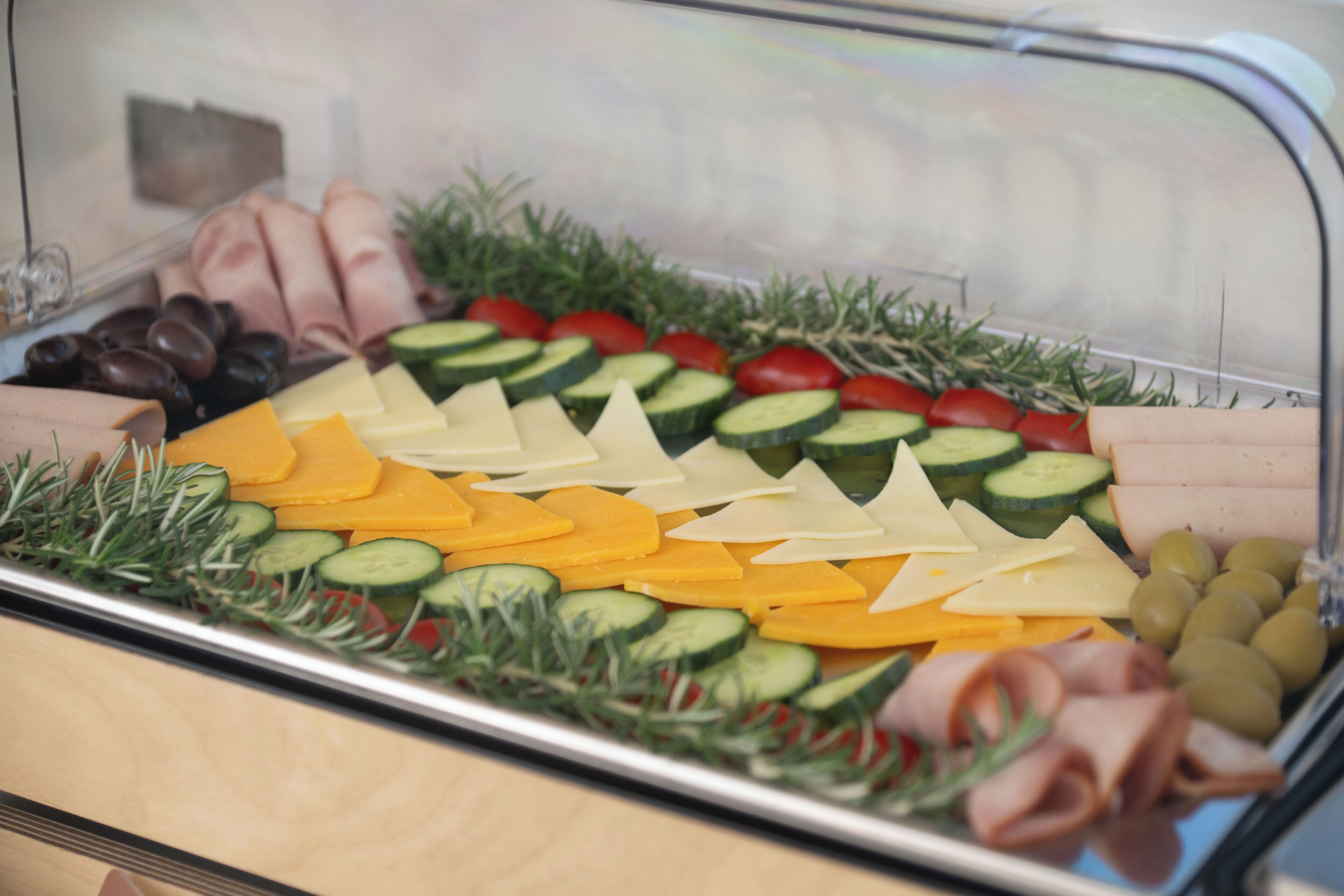 A food display with various cheeses, cured meats, and vegetables.