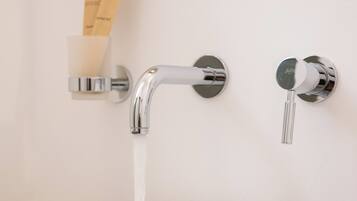A white ceramic sink with a chrome faucet, a soap dispenser, and a towel on a white countertop.