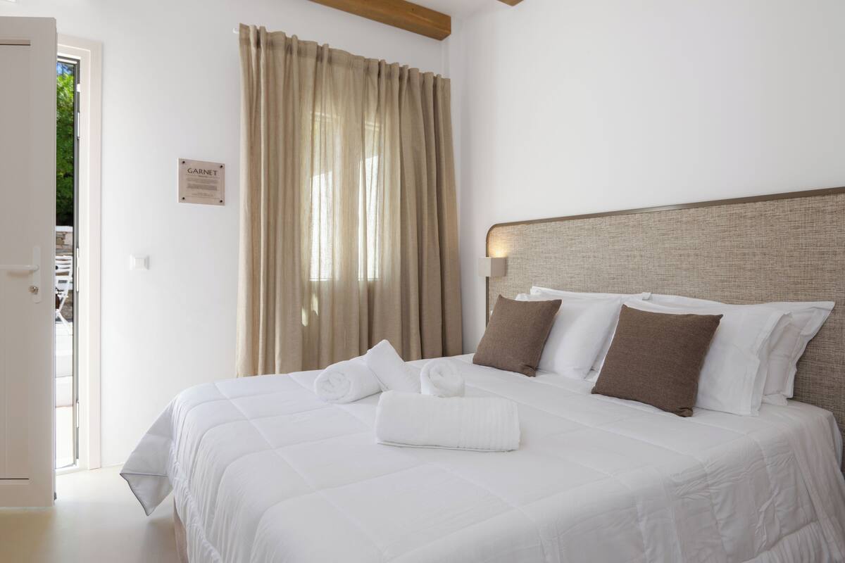 Una habitación de hotel con cama, cortinas, cabecero y un cartel en la pared.