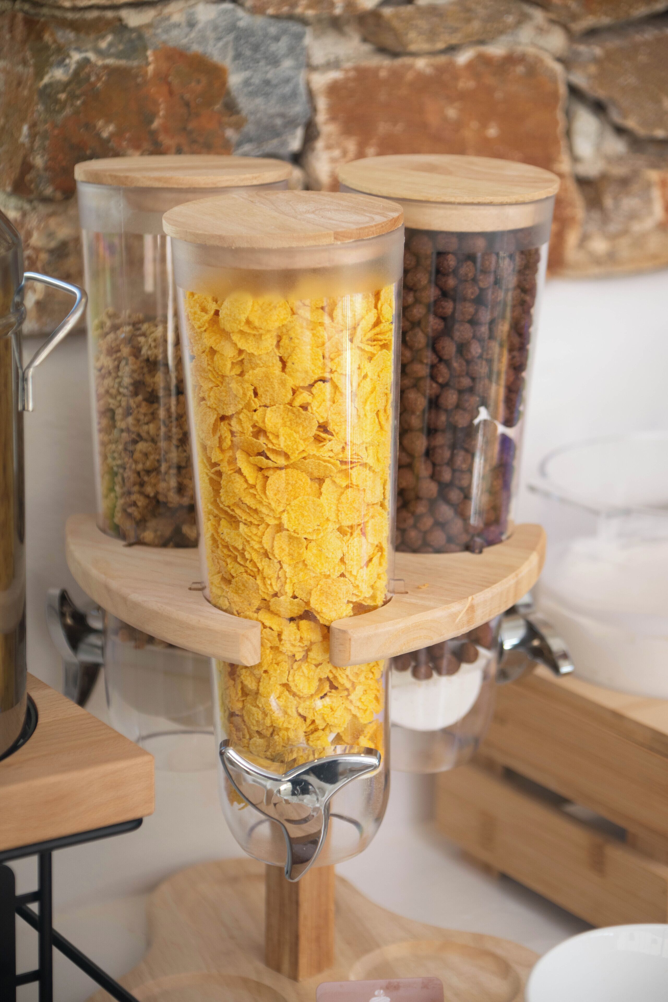 Three glass containers with lids on a wooden stand, filled with different items.