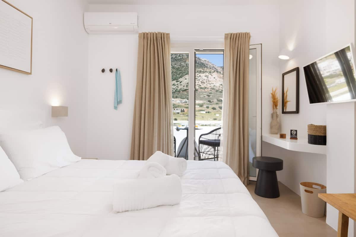 Una habitación de hotel con cama, vistas al exterior, una mesita y una silla.