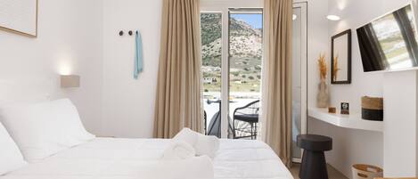 A hotel room with a bed, a view of the outdoors, a small table, and a chair.