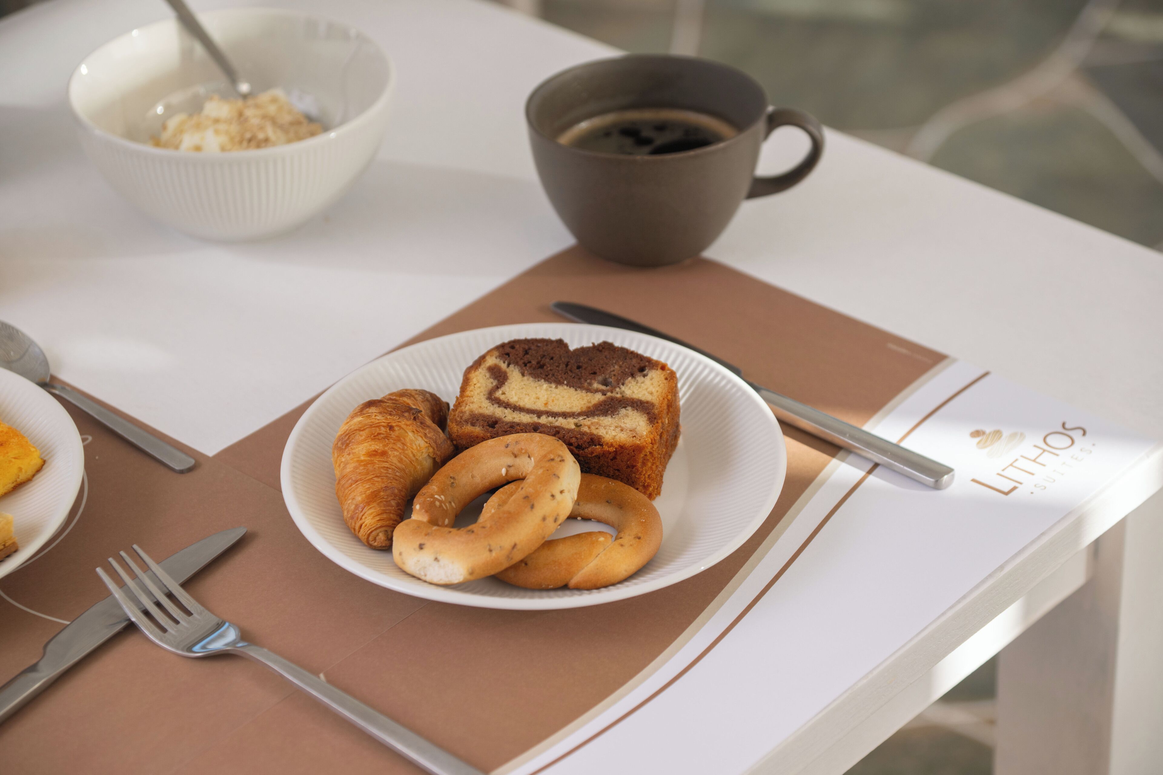 Une table mise pour le petit-déjeuner, avec une assiette de nourriture, un bol, une tasse et des couverts.