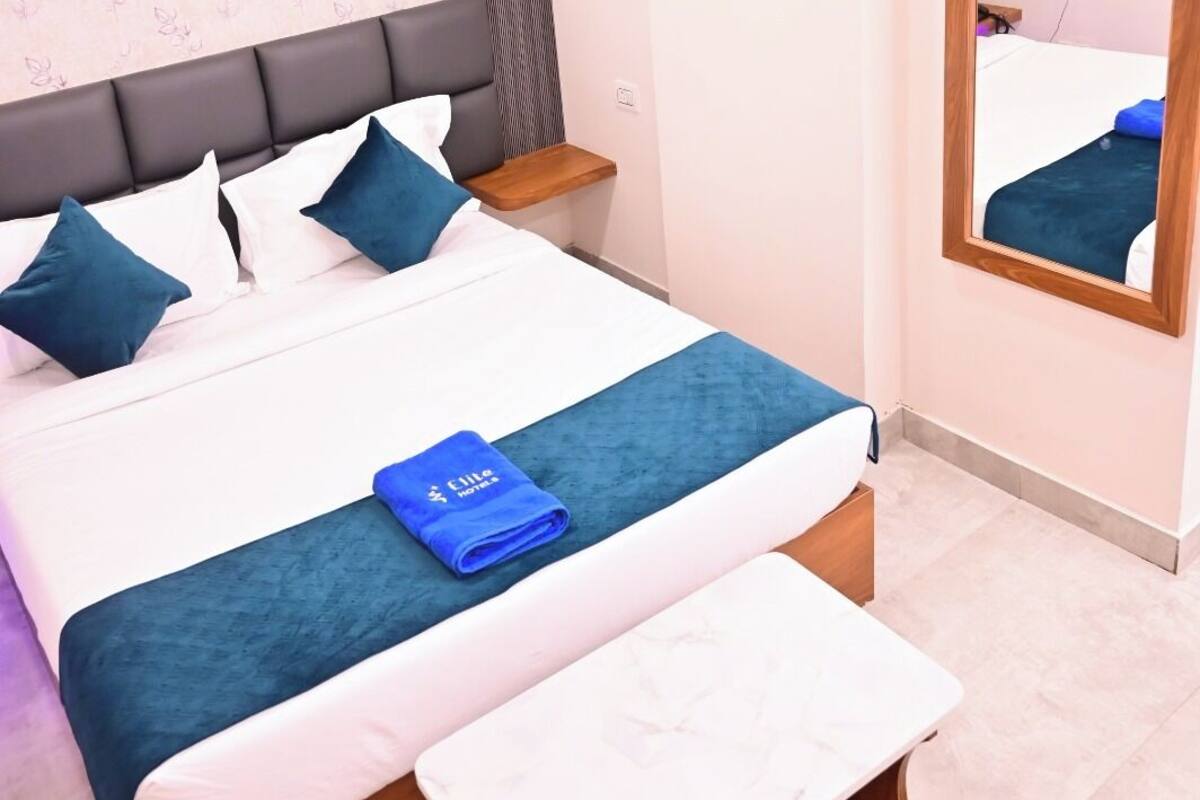 A neatly arranged bedroom with a bed, bedside tables, a mirror, and an air conditioning unit.