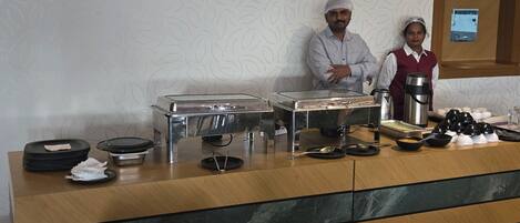 Una mesa de buffet con platos, tazones y una cafetera.