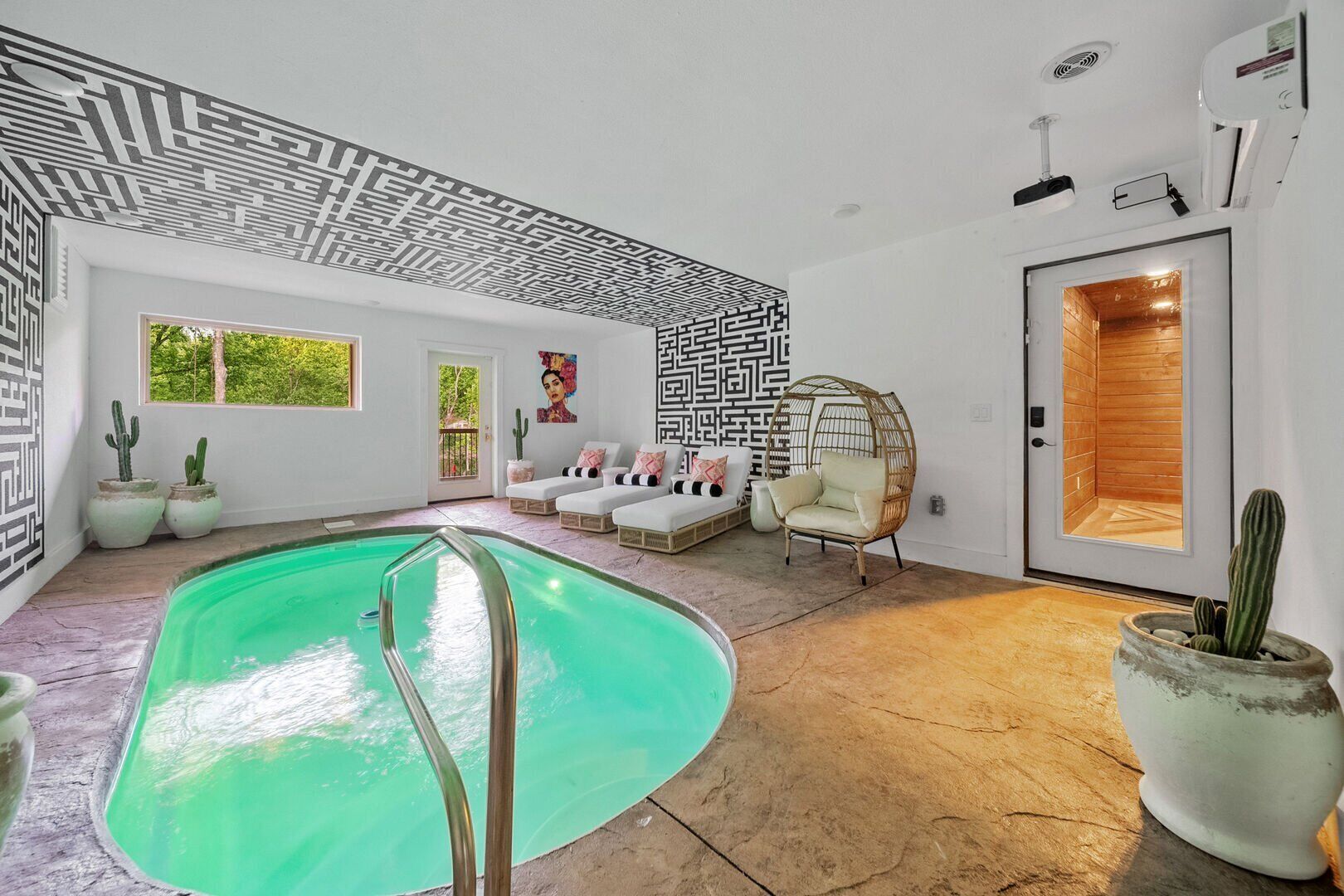 A modern interior with a swimming pool, a seating area with cushions, and a door leading to a sauna.