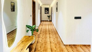 A hallway with wooden flooring, white walls, and a wooden bench. - HOTEL COCODAN (Indore)