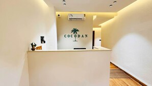 A reception desk with a sign reading "COCODAN" and a palm tree logo. - HOTEL COCODAN (Indore)