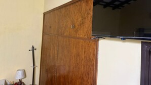 Un armario de madera con puerta espejada en una habitación de techos altos y ventilador de techo.
