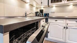 A modern kitchen with a dishwasher, stainless steel sink, and white cabinetry.
