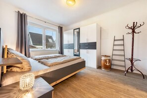 Een slaapkamer met een bed, een kledingkast, een kapstok, een ladder en een vat.