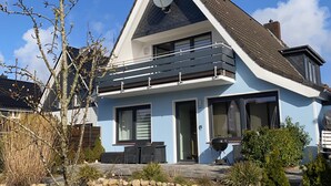 Ein modernes, zweistöckiges Haus mit einer Steinwand, einem Balkon und einer Satellitenschüssel.
