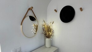 A bathroom with a white vanity, a mirror, a black circular decoration, and a vase with dried plants. - Duplex with private terrace and parking 15 minutes from Seville (Dos Hermanas)