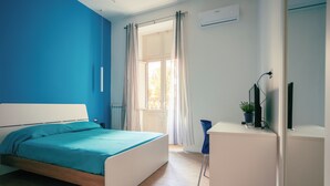 Een slaapkamer met een bed, een bureau en een raam met gordijnen.