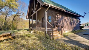 A log cabin with a porch, a picnic table, and a stone wall. - Cabin Along Rough River! Views, Fire Pit & Grill (Falls of Rough)