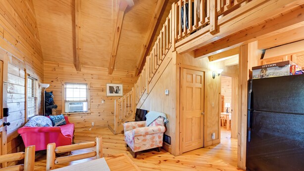 A wooden cabin interior with a wooden staircase, a dining area, and a kitchen with a refrigerator. - Cabin Along Rough River! Views, Fire Pit & Grill (Falls of Rough)