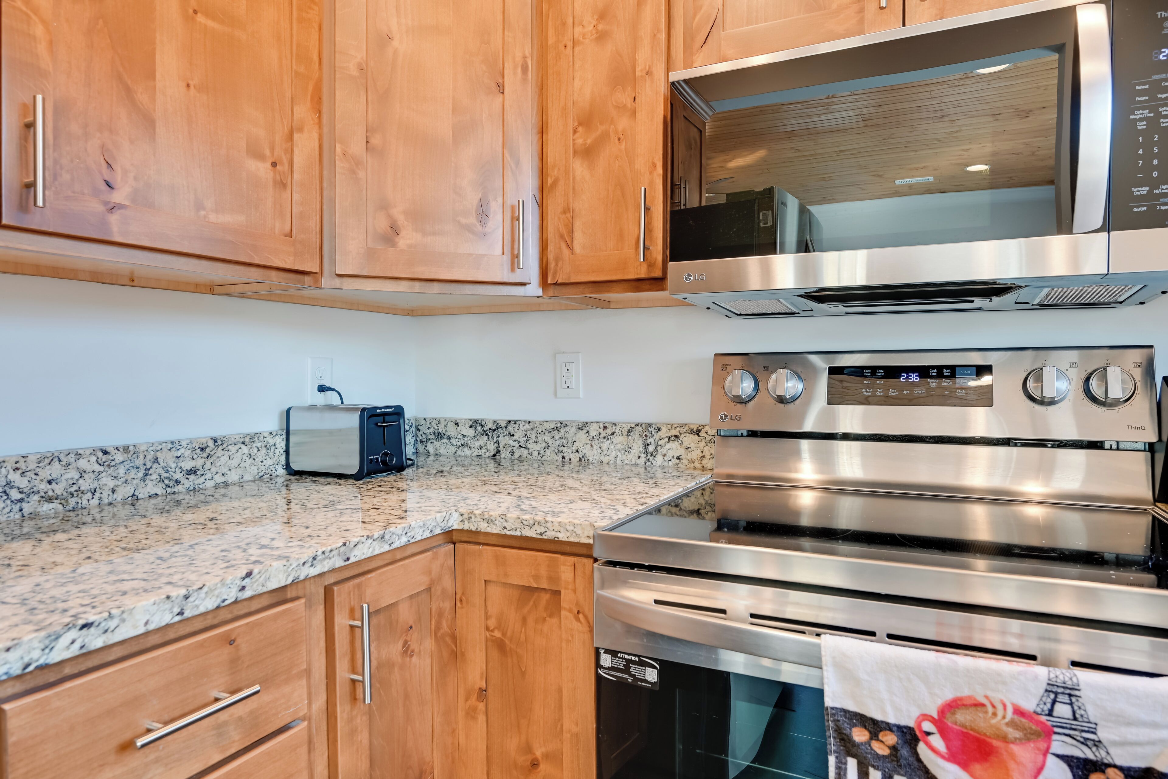 A kitchen with wooden cabinets, a microwave, a toaster, and a stainless steel oven.
