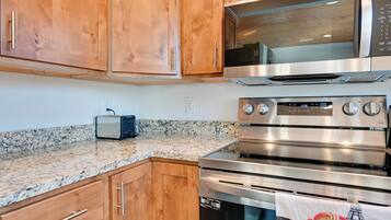 A kitchen with wooden cabinets, a microwave, a toaster, and a stainless steel oven.