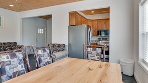 Un comedor con una mesa de madera y sillas estampadas, una cocina con armarios de madera y un ventilador de techo.