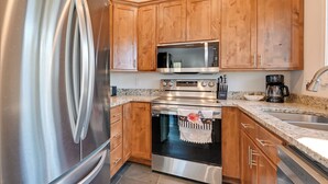 Una cocina con armarios de madera, electrodomésticos de acero inoxidable, encimeras de granito y horno empotrado.