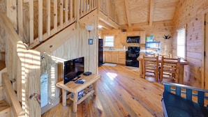 L’intérieur d’une cabane en bois comprend un escalier, un espace de vie, une cuisine et un coin repas.
