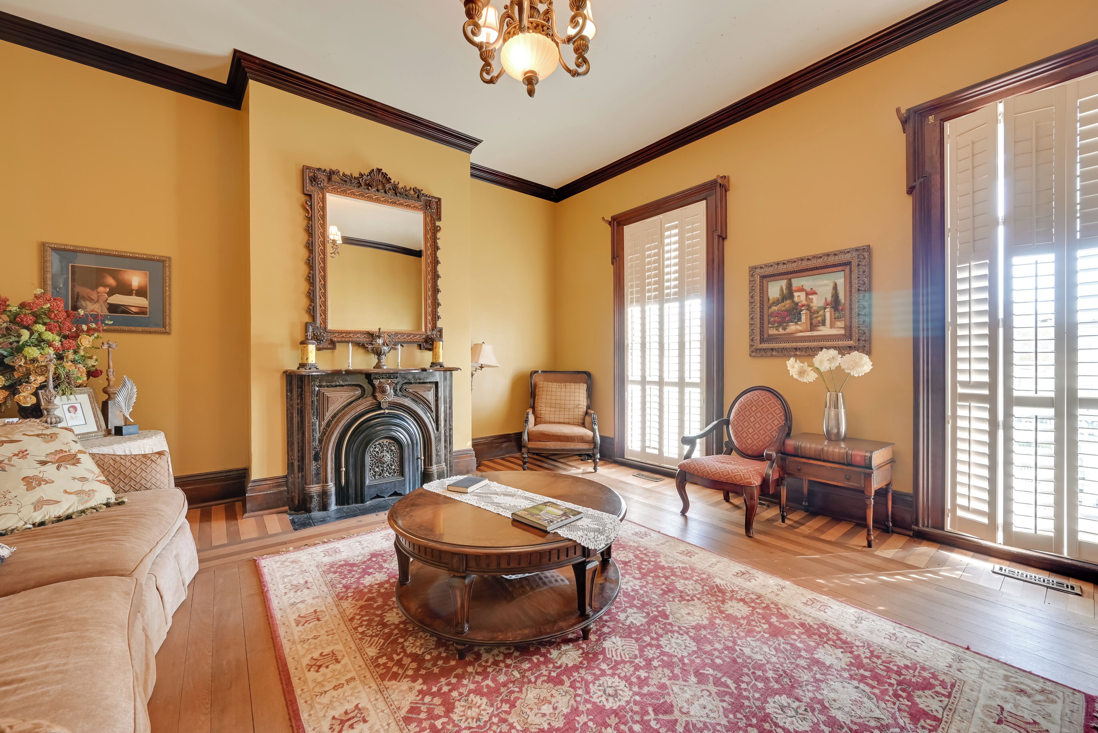 A traditional living room with a fireplace, a round coffee table, and a large mirror.