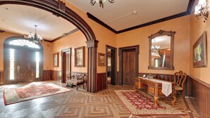 Um quarto espaçoso com um padrão de piso em padrão marquês, uma escrivaninha de madeira grande com uma cadeira e um candelabro.