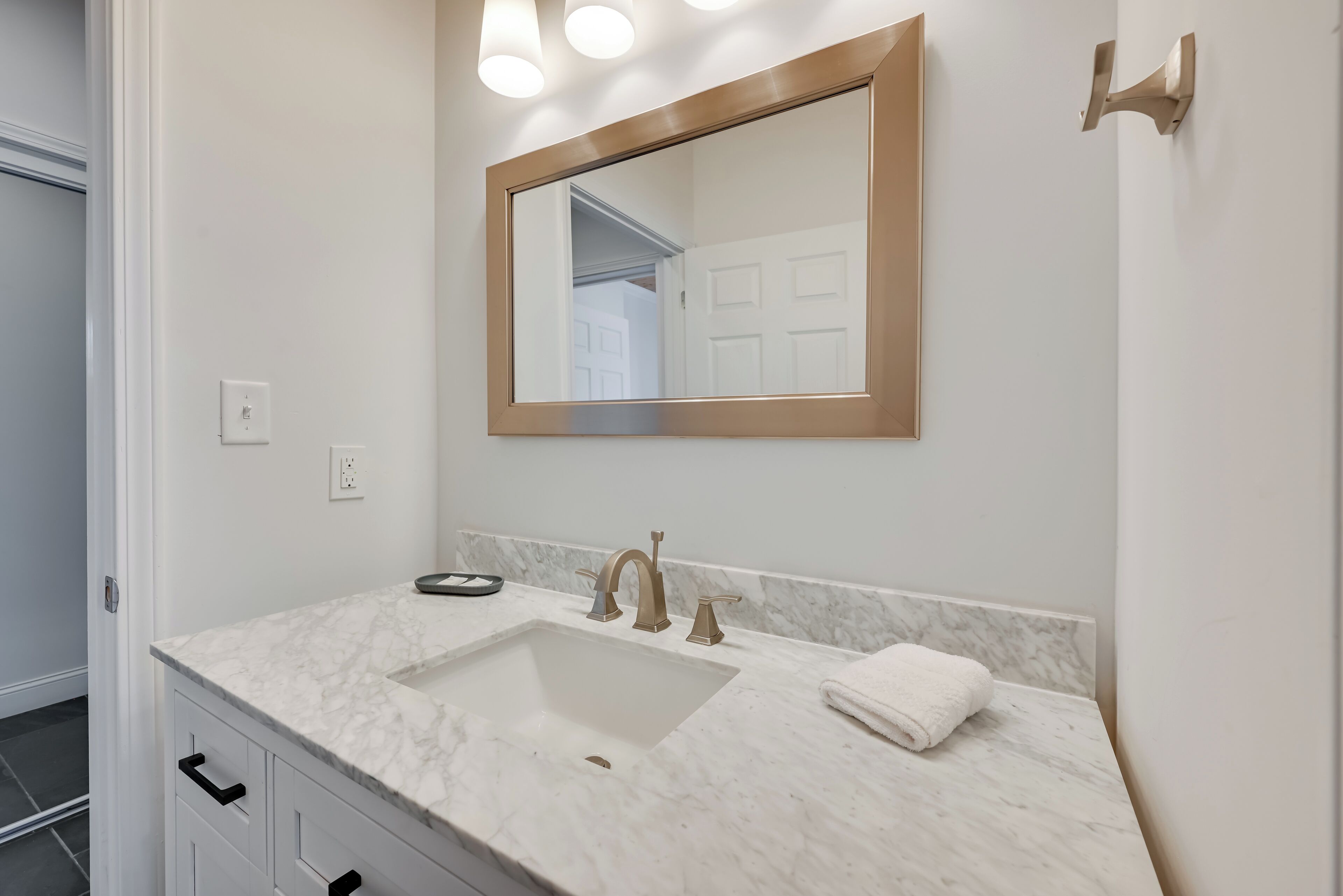 A bathroom with a white marble sink, a large mirror, and a towel on the counter.