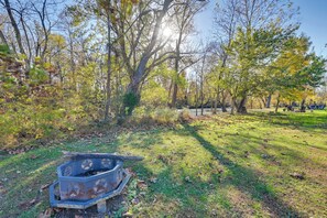 A park with a hexagonal fire pit, trees, and a grassy area.
