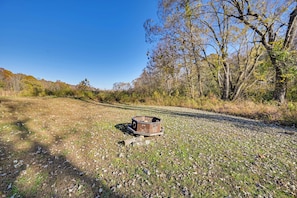 An outdoor area with a metal structure, possibly a trash bin, surrounded by trees and a gravel path.
