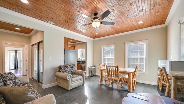 A spacious living room with a high ceiling, a dining area with wooden chairs, and a kitchen in the background. - Fish & Unwind! Rough River Hideaway w/ Deck (Falls of Rough)