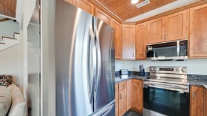 A modern kitchen with stainless steel appliances, wooden cabinets, and a granite countertop. - Fish & Unwind! Rough River Hideaway w/ Deck (Falls of Rough)
