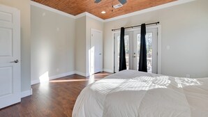 A bedroom with a large bed, wooden flooring, a ceiling fan, and a view through a window. - Fish & Unwind! Rough River Hideaway w/ Deck (Falls of Rough)