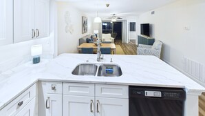 A modern kitchen with white cabinetry, a built-in dishwasher, and a marble countertop.