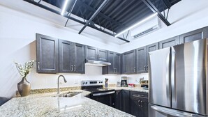 Eine moderne Küche mit Granit Arbeitsplatten, Edelstahlgeräten und dunklen Schränken.