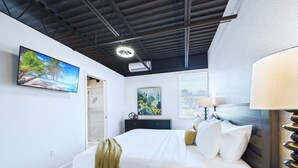 Ein modernes Hotelzimmer mit einem Bett, einem Schreibtisch, einer Lampe, einem Gemälde und einem Fenster.