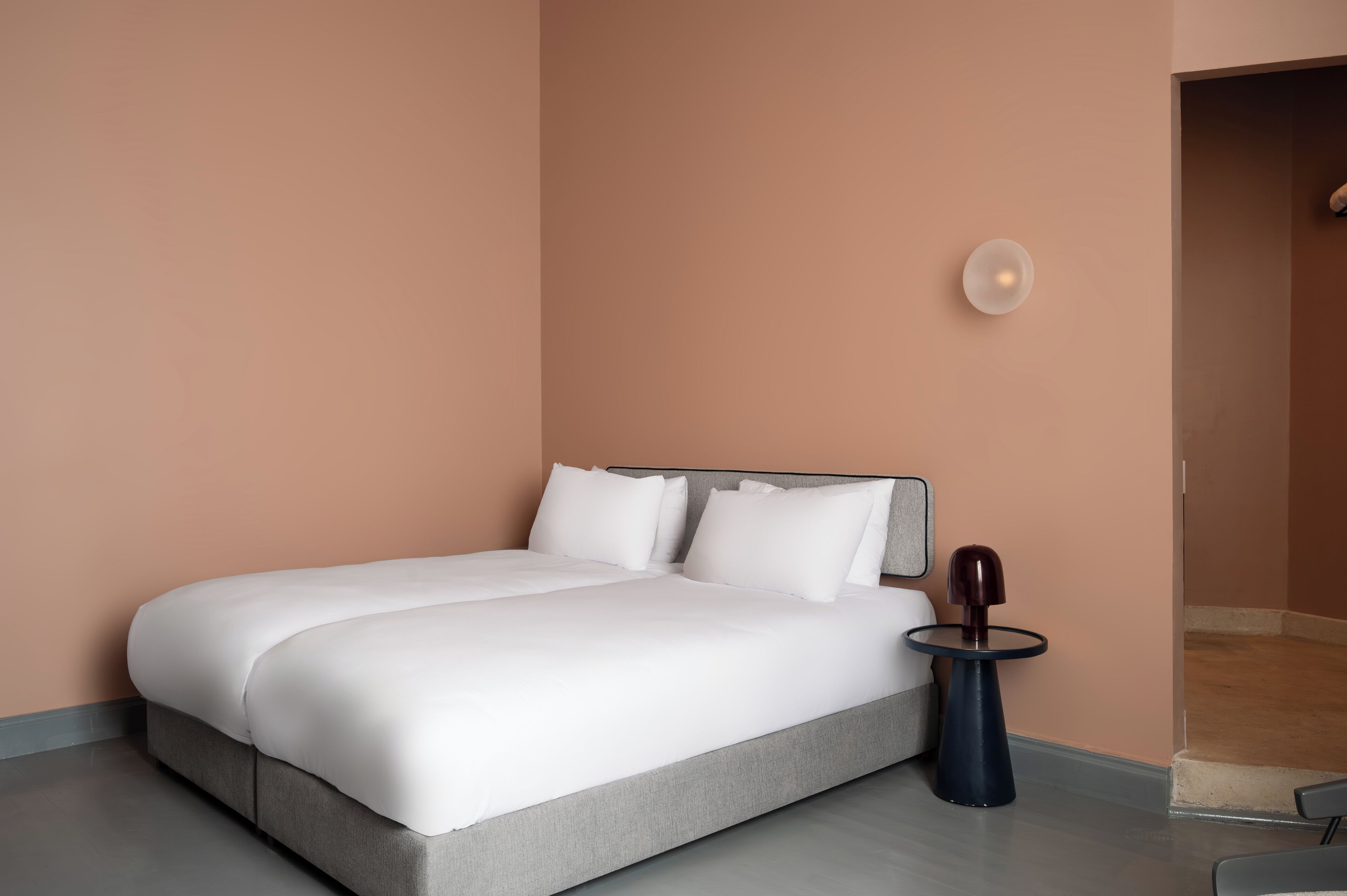 Een moderne slaapkamer met een groot bed, een nachtkastje en een wandlamp.