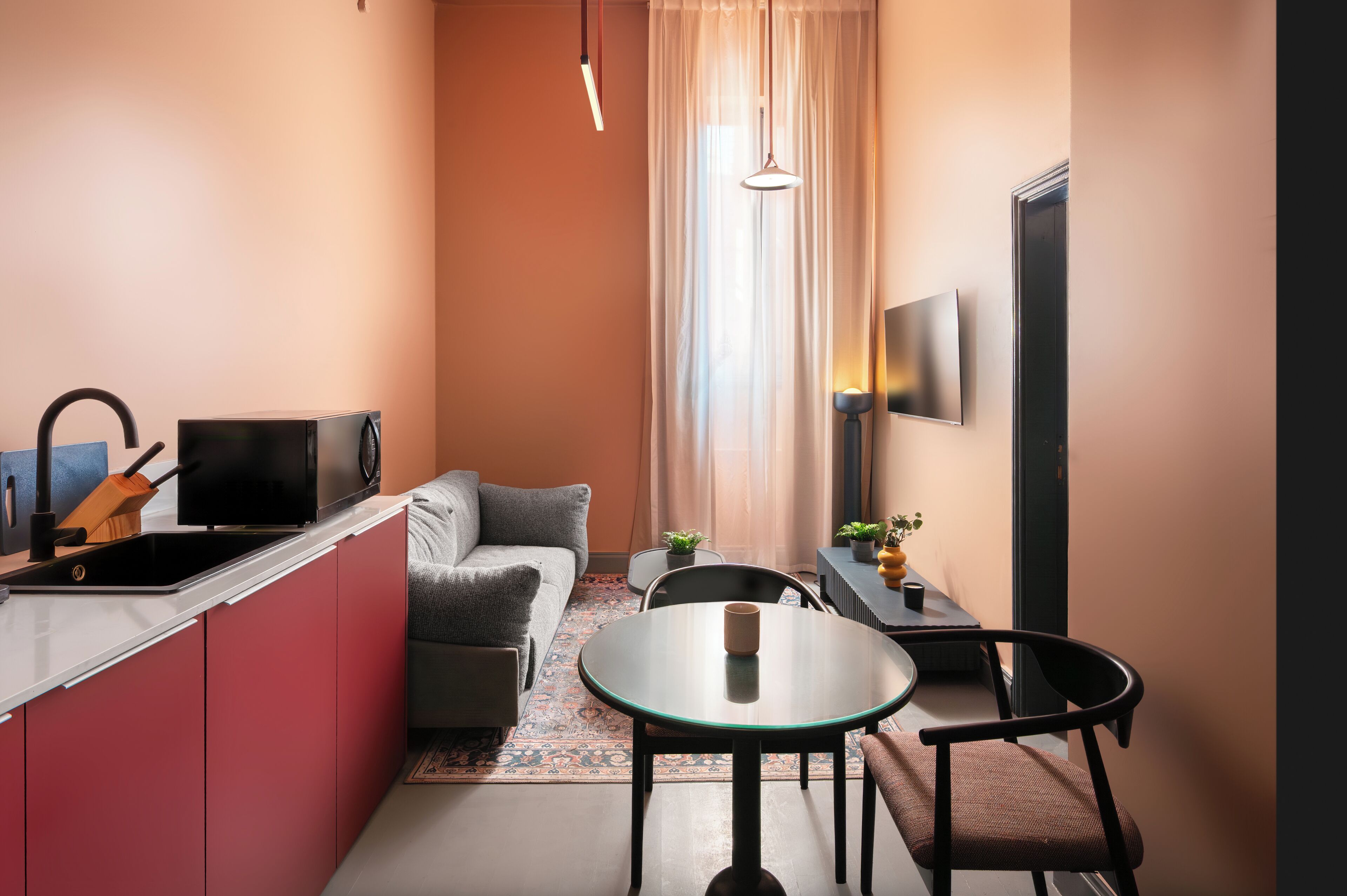 Une cuisine compacte avec un coin repas, un canapé et un téléviseur fixé au mur.
