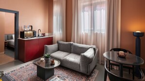 A modern living room with a grey sofa, a small coffee table, a red cabinet, and a dining table with chairs. - Brassbell grey apartments Bidair House (Cairo)