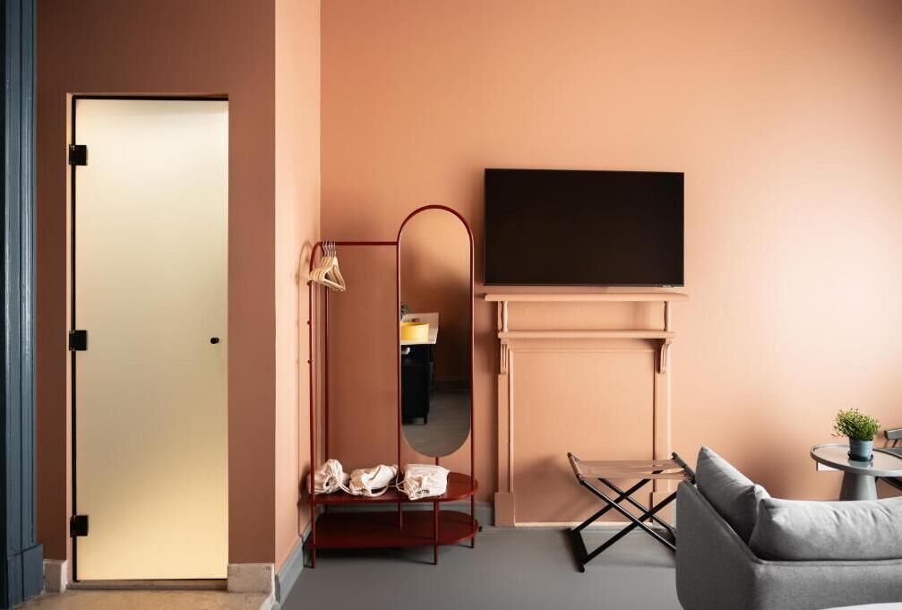 Una sala de estar moderna con un sofá, un televisor sobre la chimenea y un espejo que refleja la habitación.