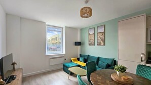 A modern living room with a dining area, a sofa set, a coffee table, and a view of a building through a window.