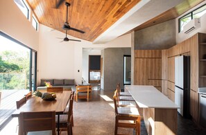 A modern kitchen with wooden cabinetry, a large island, and a dining area with wooden chairs and a table.