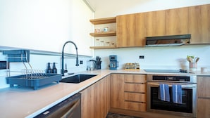 Une cuisine moderne avec des meubles en bois, un lave-vaisselle en acier inoxydable et un four encastré.