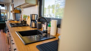 Cocina moderna con estufa a gas, pileta, cafetera y ventana con vista al exterior.